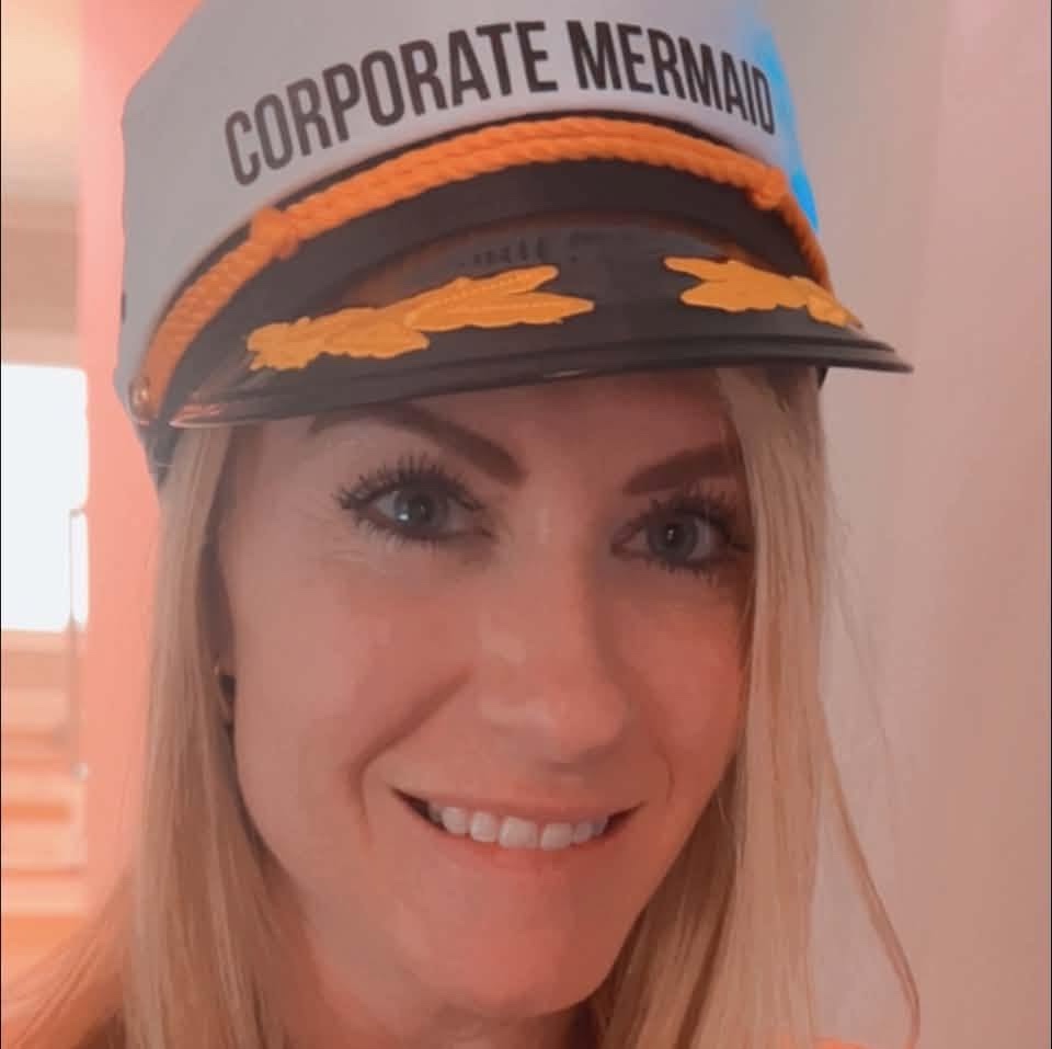 Brooke Beach, founder of Corporate Mermaid, smiling in her Corporate Mermaid captain's hat